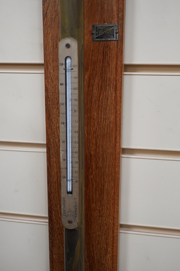 A 20th century lacquered brass marine stick barometer and thermometer by A. Gallenkamp & Co. Ltd., London, with a silvered scale, mounted on a faded oak plaque, 107cm high overall